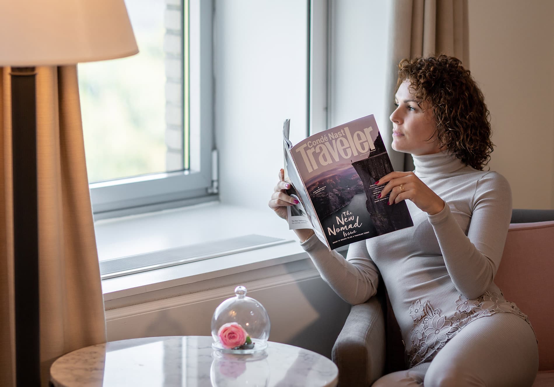 woman in hotel suite reading conde nast magazine